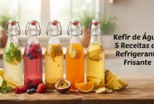 Foto horizontal de 5 garrafas de vidro com kefir de água de frutas e ervas sobre mesa rústica. No lado direito, o texto "Kefir de Água: 5 Receitas de Refrigerante Frisante".