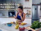 Mulher sorrindo na cozinha limpa com frutas na bancada.